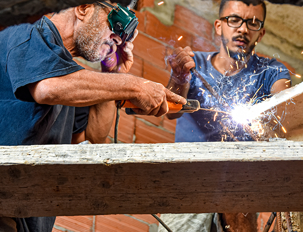 older man teaches another on the job